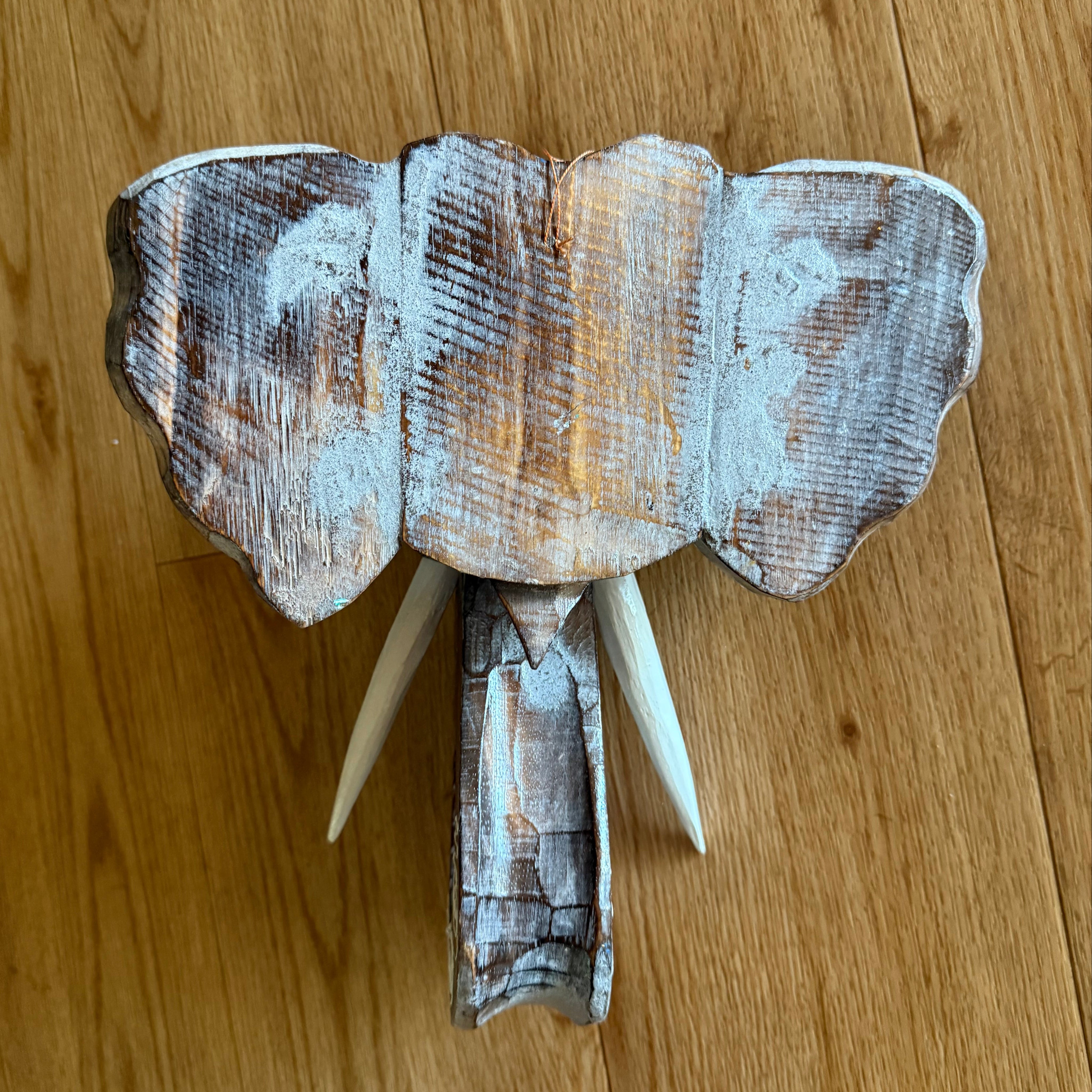 Weathered wooden elephant head sculpture with tusks