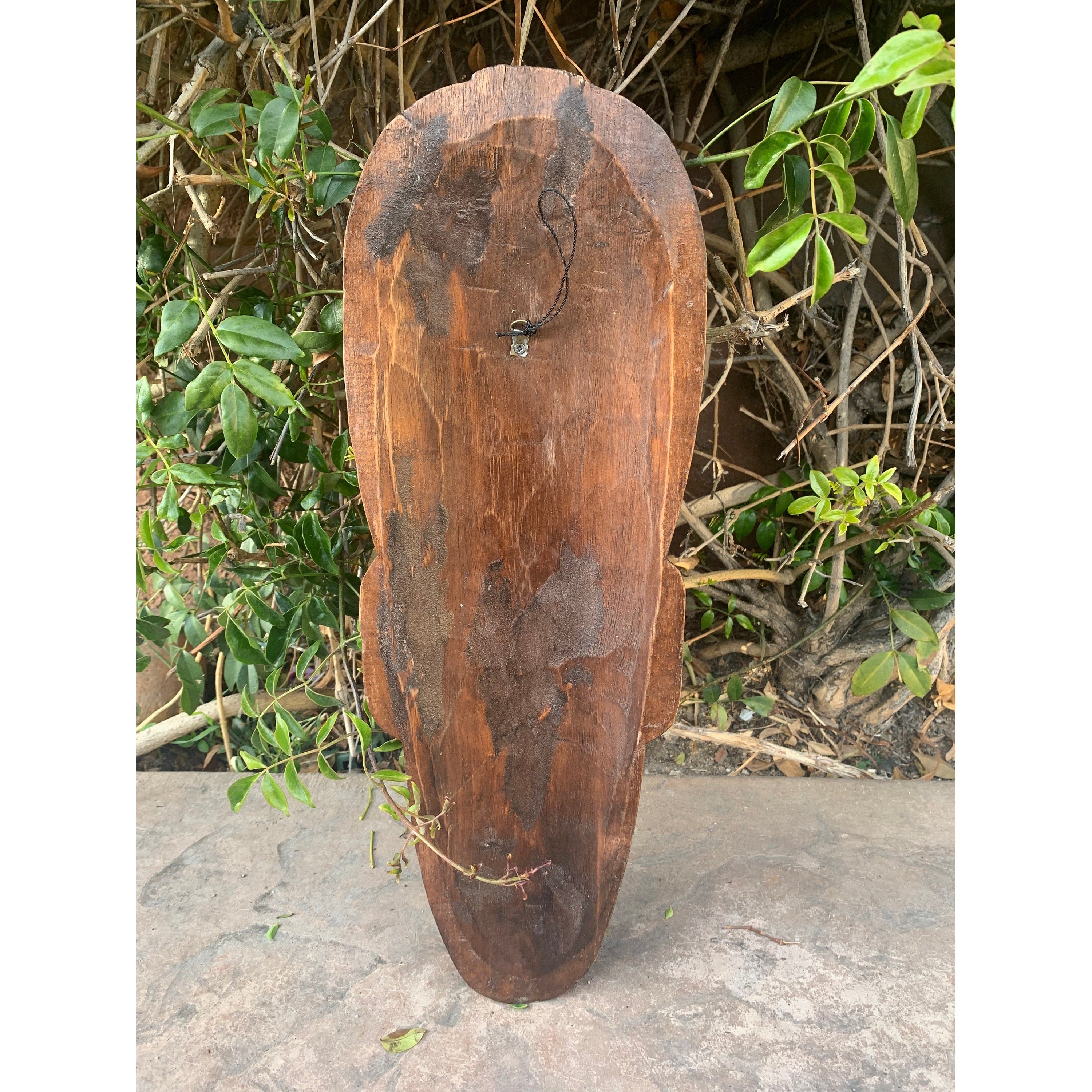 Weathered wooden shield-shaped plaque with a small metal hook and hanging cord