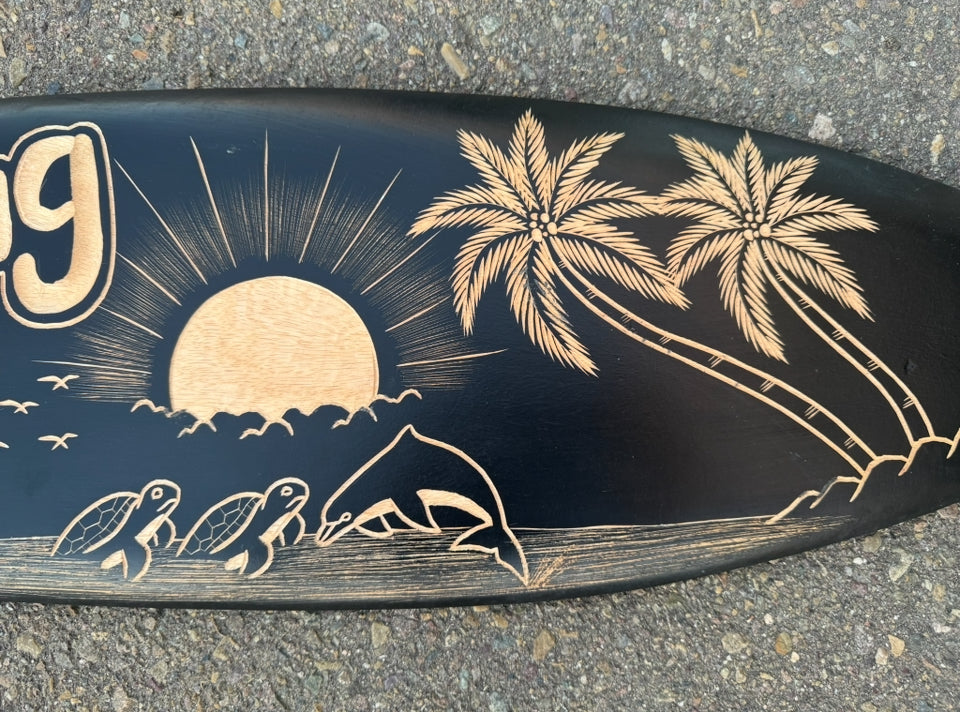 Wood-burned surfboard art of a sunset, palm trees, and sea turtles along the shore.