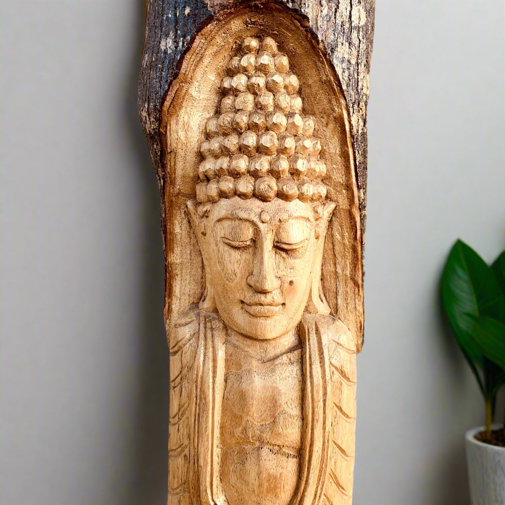 Carved wooden Buddha head on a log with a serene expression