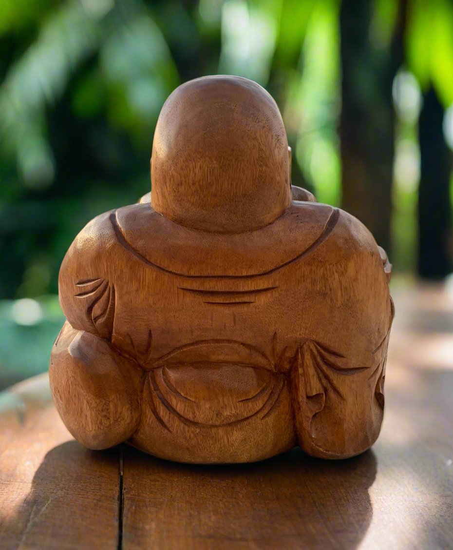 Back view of a carved wooden Buddha statue outdoors in a garden