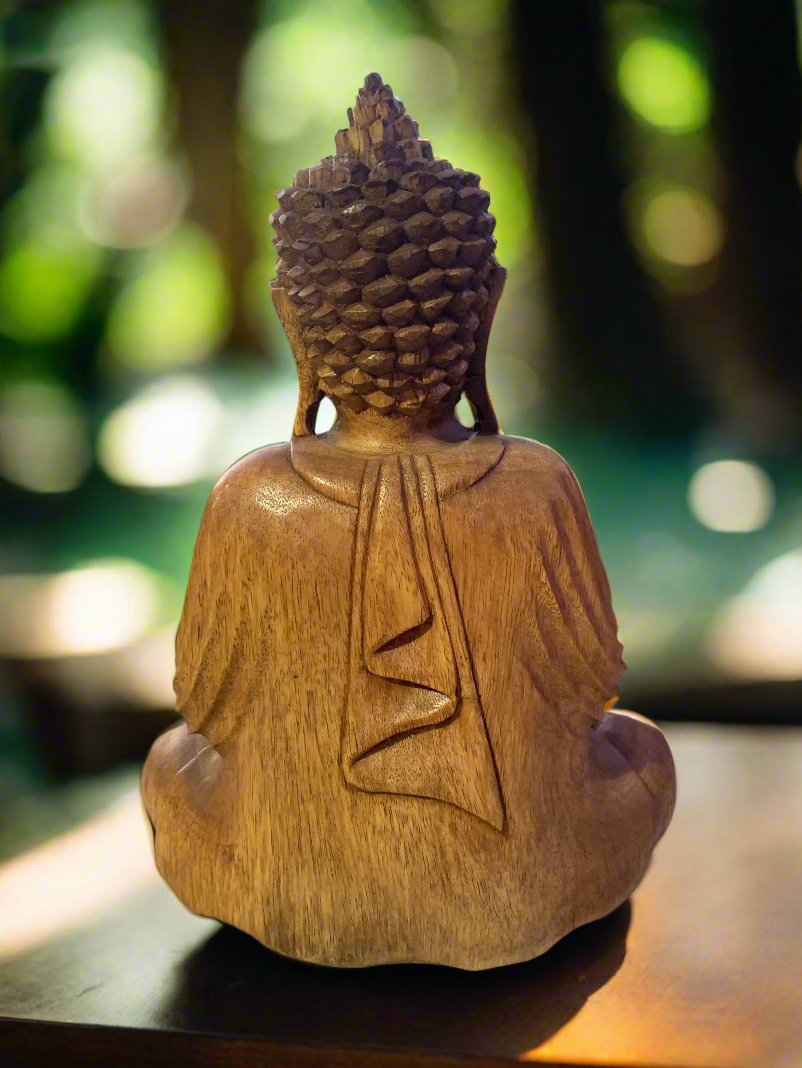 Rear view of a wooden Buddha statue with detailed curls and flowing robe, set against a green background.