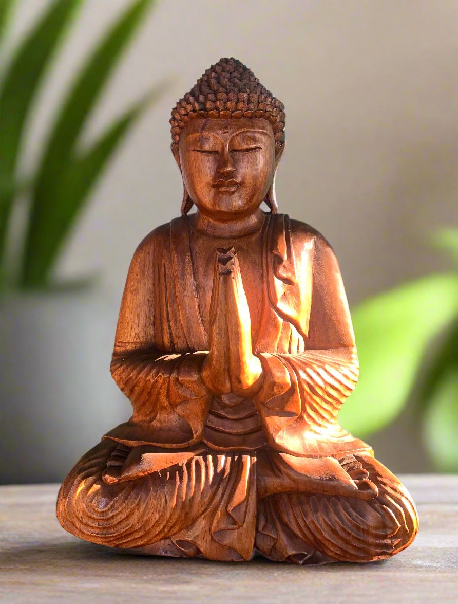 Wooden Buddha statue meditating with hands in prayer