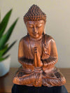 Wooden Buddha statue with hands in prayer pose