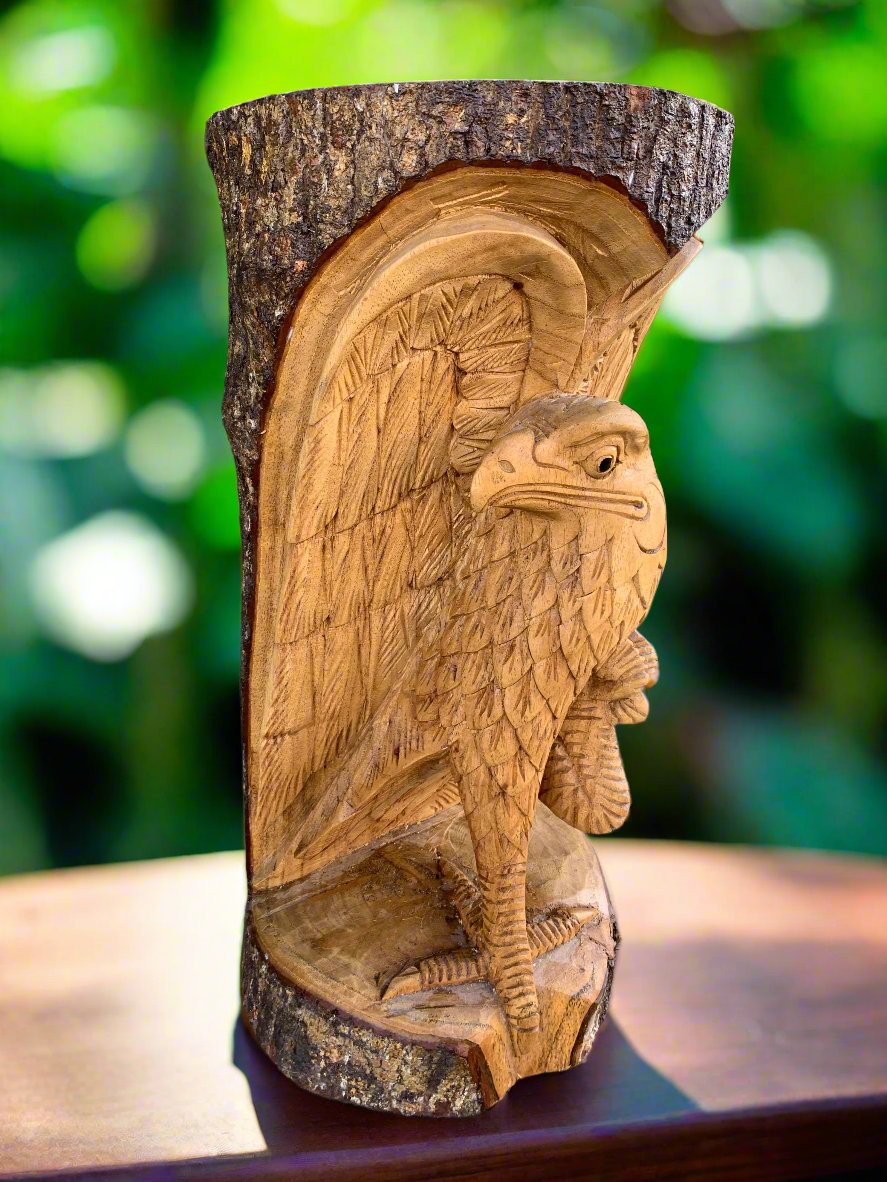 Wooden carved bird sculpture perched on a tree trunk outdoors