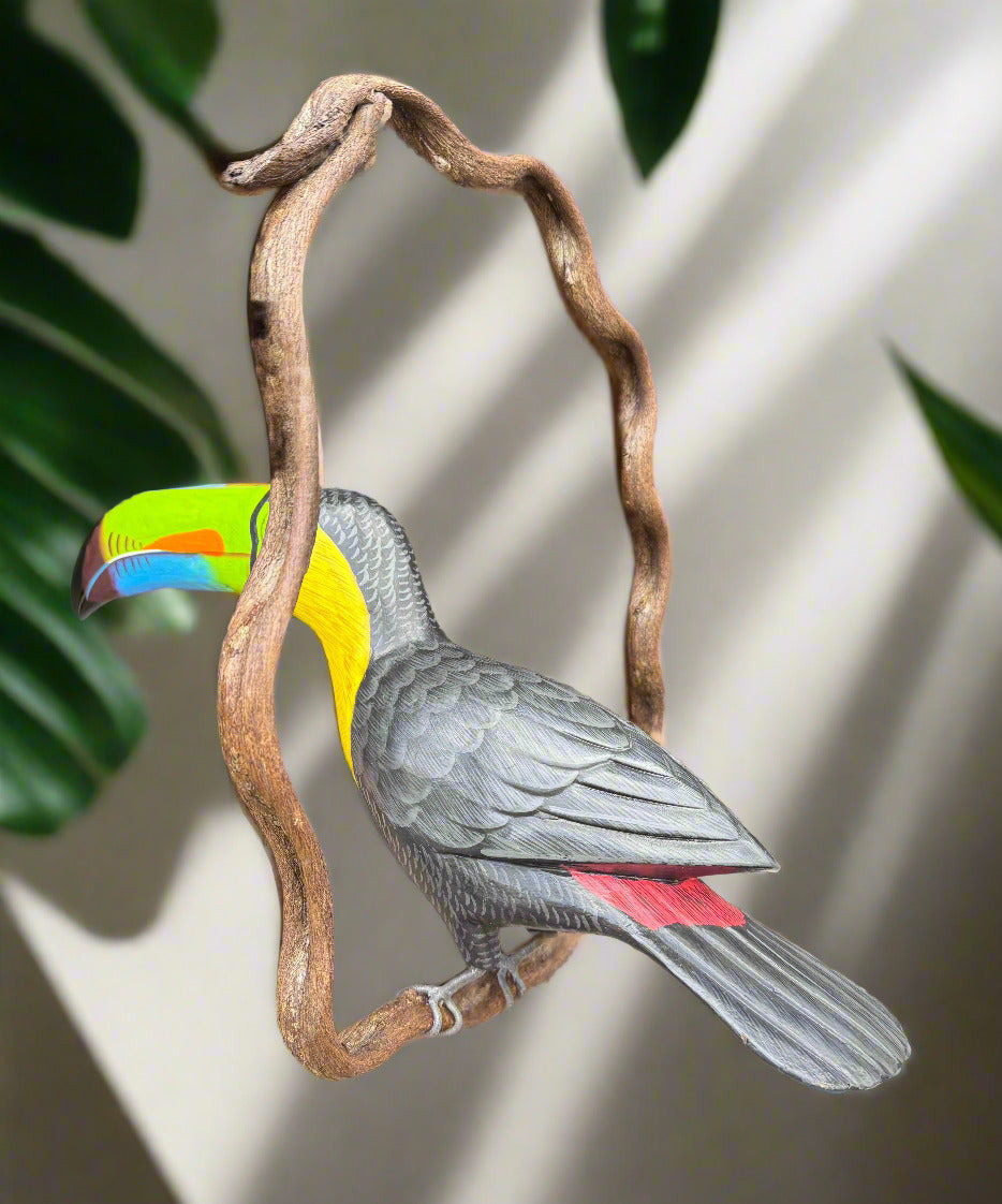 Wooden carved bird sculpture with rainbow beak perched on a twisting branch