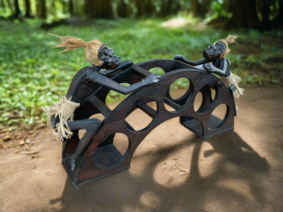 wooden carved bridge sculpture featuring two figures on a curved arch in a forest