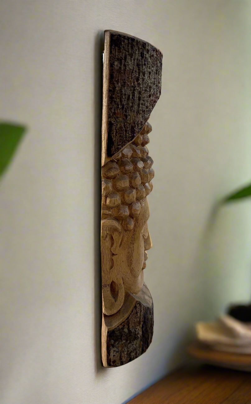 Side profile of a wooden carved face relief mounted on a bark slab wall plaque