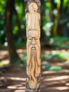 Wooden carved face on a tree trunk in a forest.