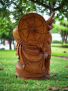 Back view of a wooden carved statue with a round patterned disk in a park