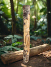 carved wooden totem pole with a bearded face in a forest
