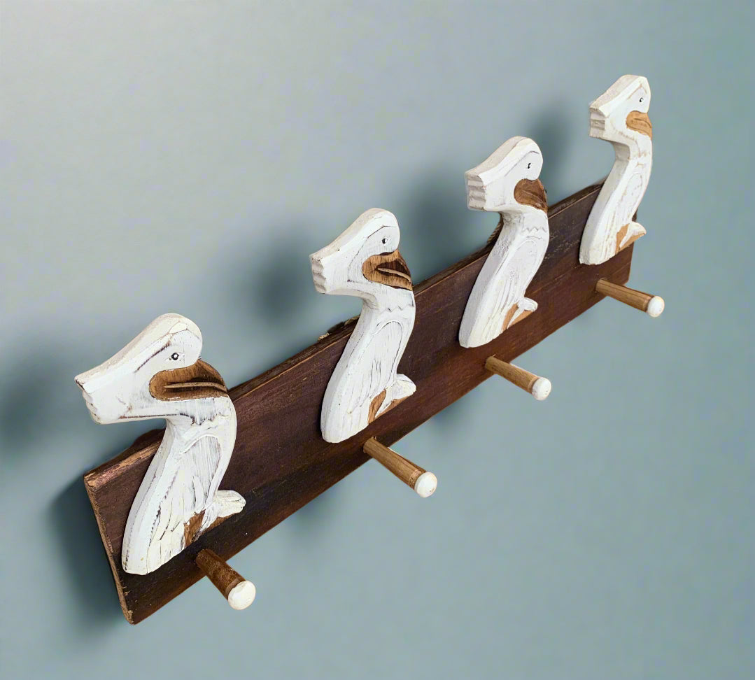 Four carved white duck heads mounted on a dark wooden coat rack with pegs