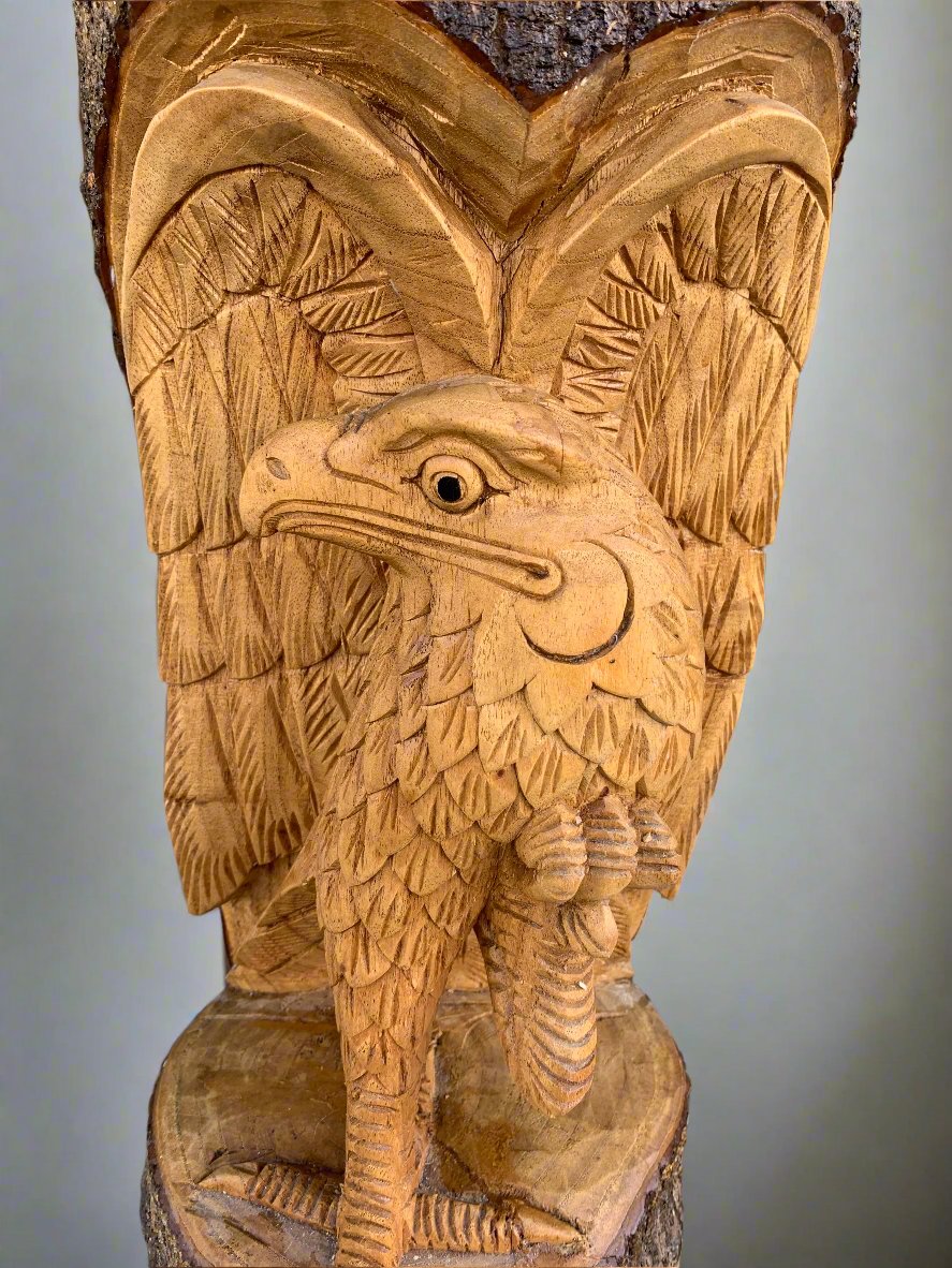 intricate wooden eagle carving with spread wings on a tree trunk base