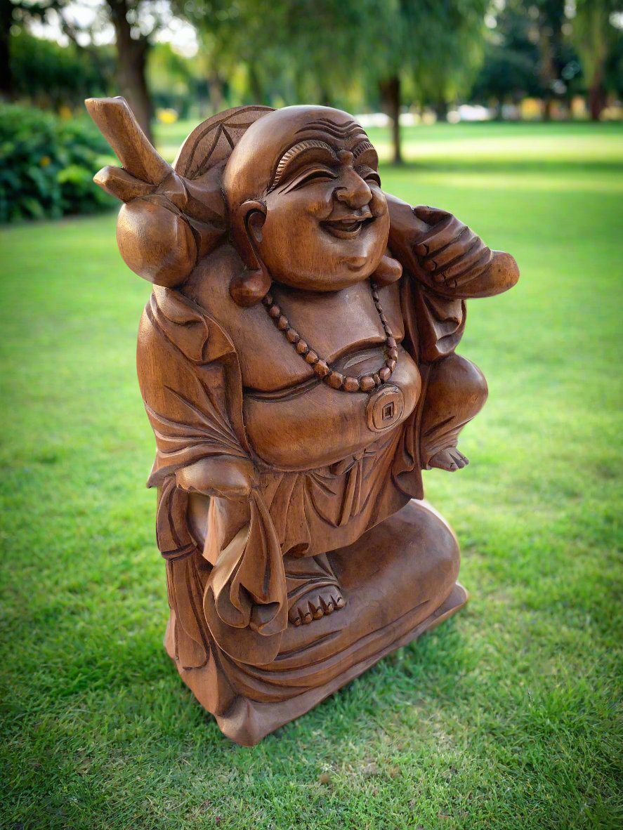 Wooden Laughing Buddha statue on green park lawn