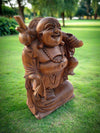 Wooden Laughing Buddha statue on green park lawn
