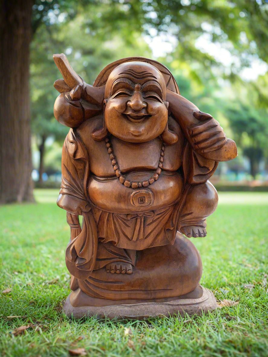 Wooden Laughing Buddha statue in a sunny park setting