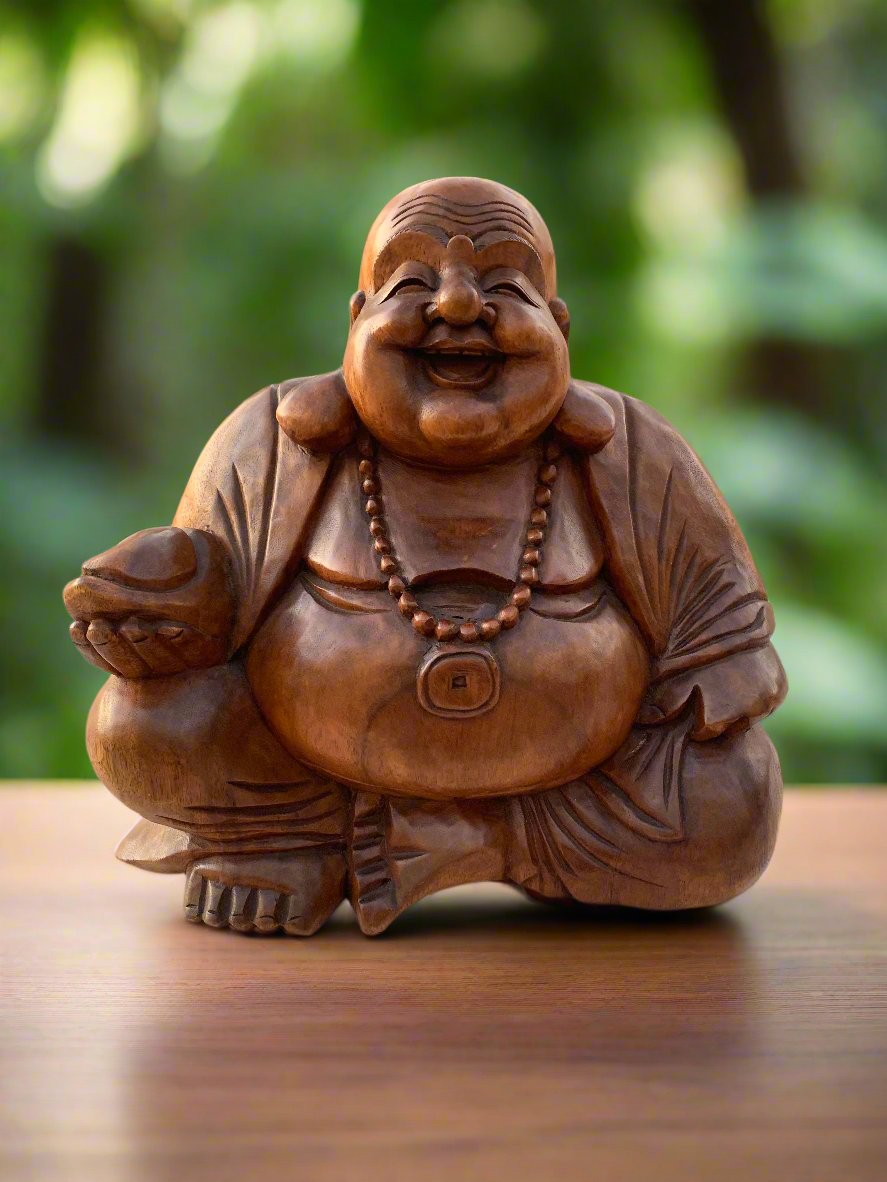Wooden laughing Buddha statue with beads, sitting cross-legged on a wooden table outdoors
