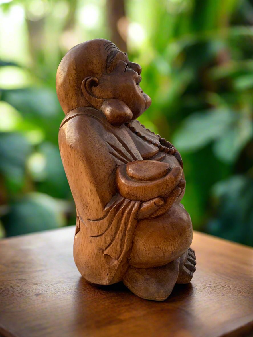 Wooden laughing Buddha statue with prayer beads on a wooden table in a garden
