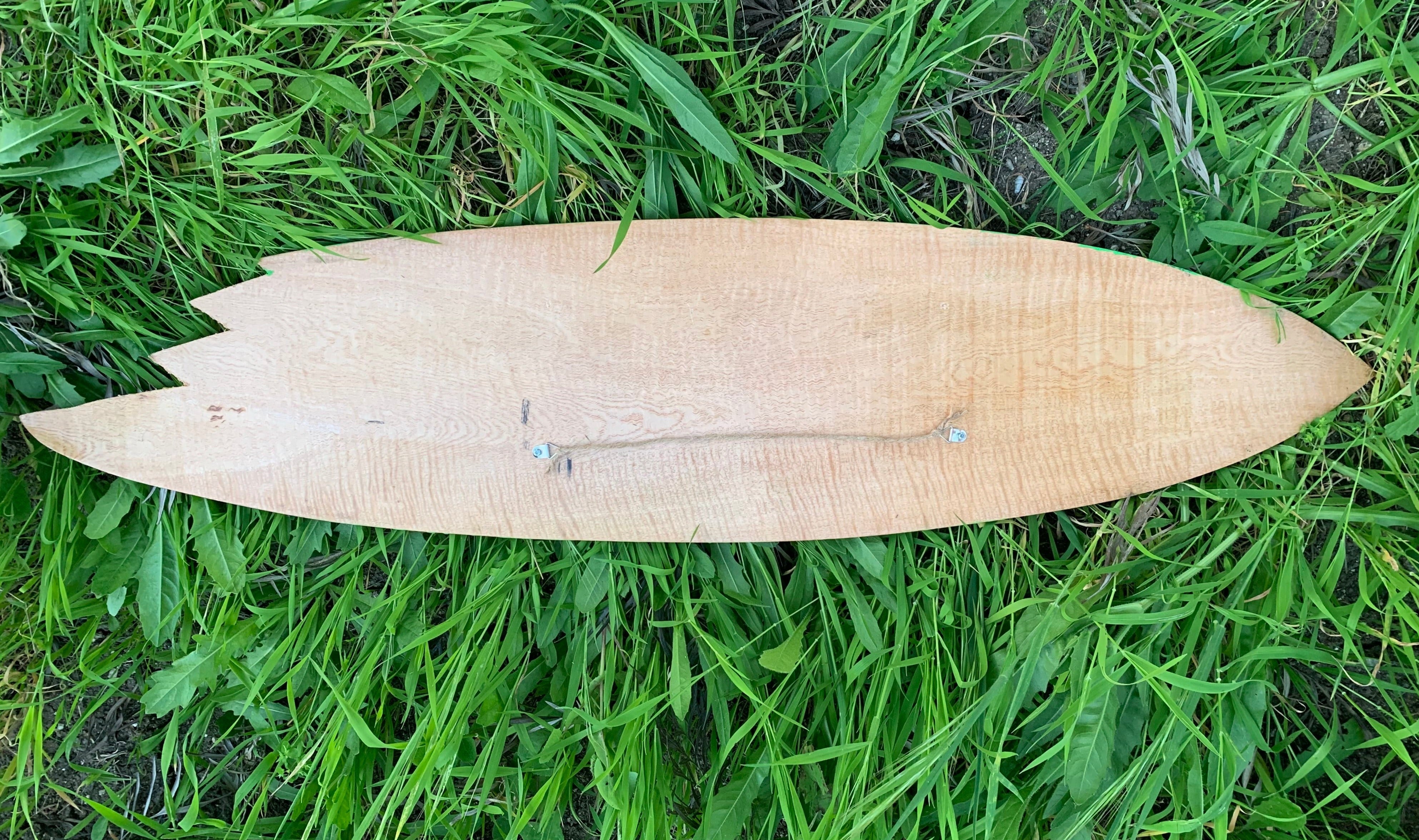 Wooden leaf-shaped board with a central stringer resting on green grass