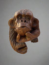 Wooden carved monkey figurine with textured fur and a thoughtful pose