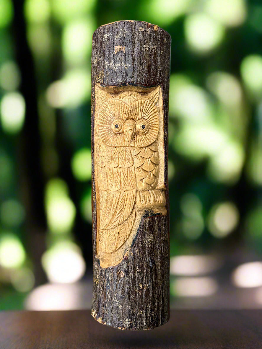Wooden owl carving on a vertical tree log with carved feather details