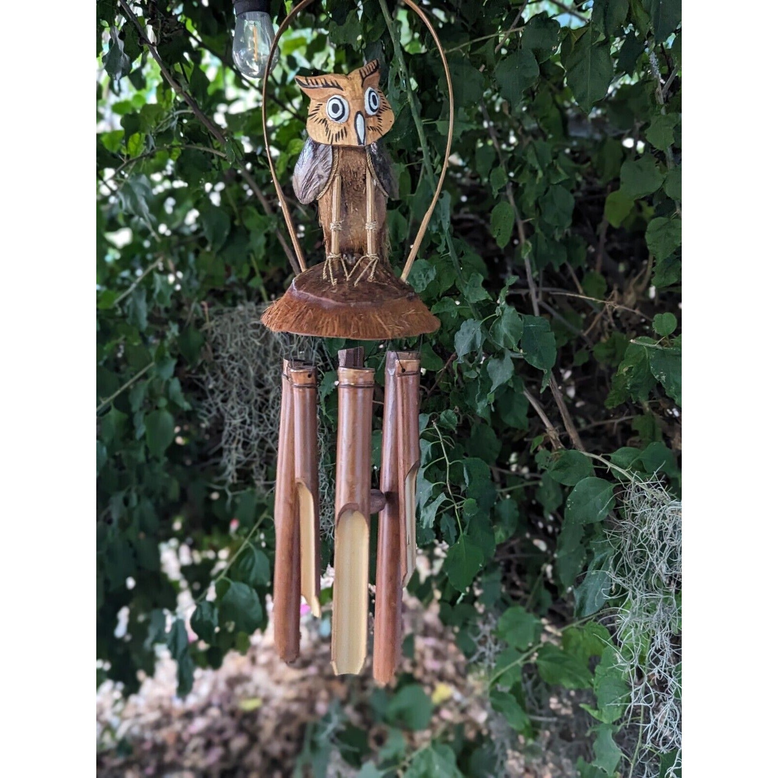 Wooden owl wind chime with bamboo tubes hanging in a garden
