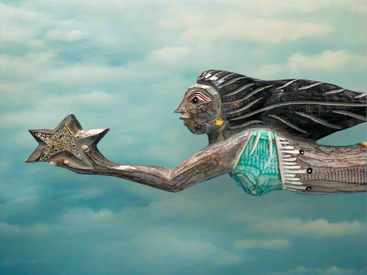 Wooden sculpture of a girl with flowing hair in a turquoise dress reaching for a star in a cloudy sky.