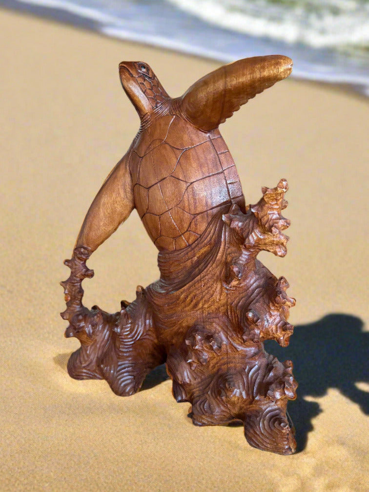 Wooden sea turtle sculpture on sandy beach with the ocean in the background