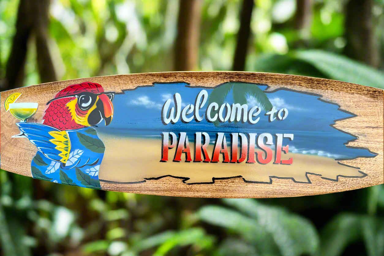 Wooden sign featuring a colorful parrot and the words Welcome to Paradise in a tropical setting