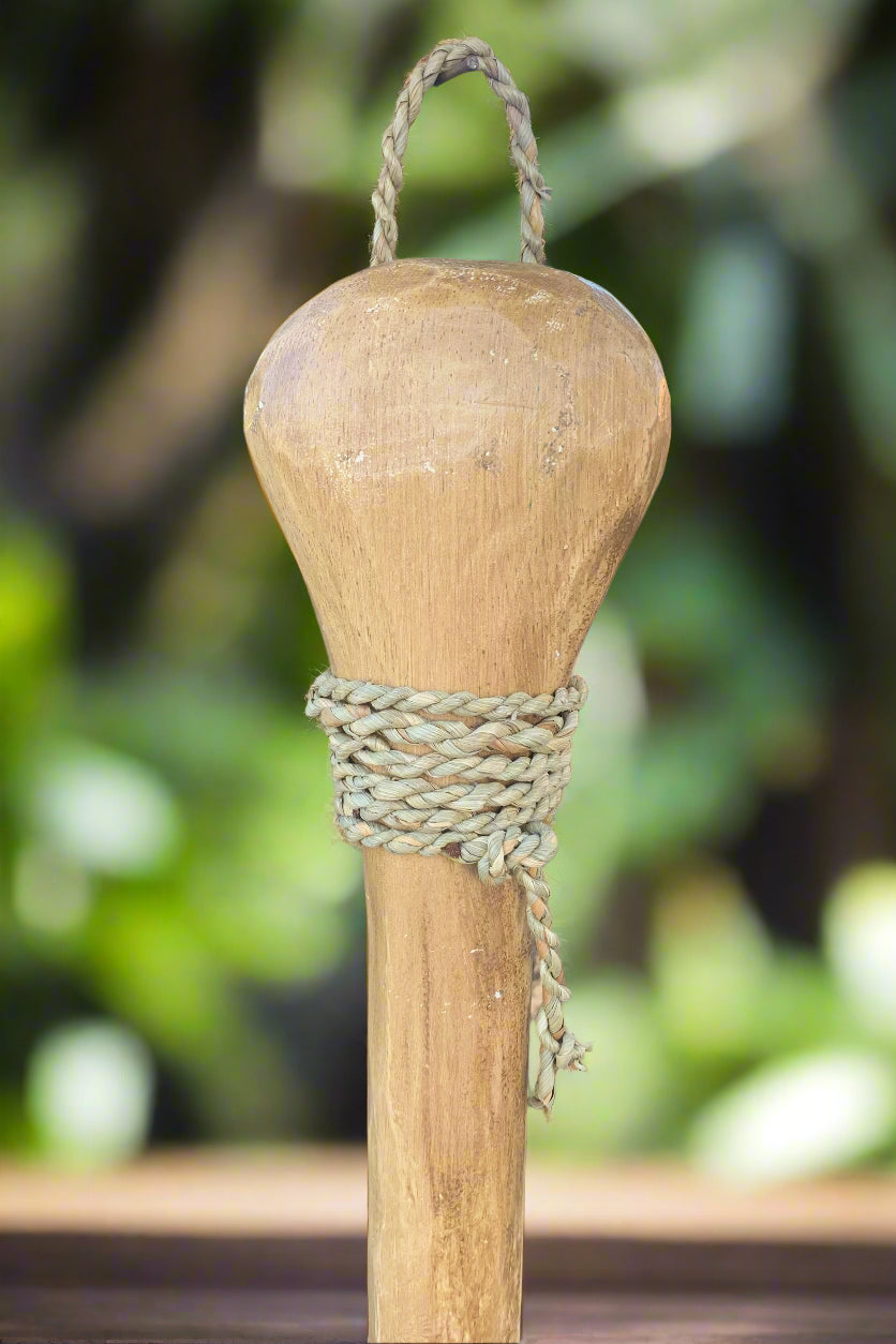 wooden post with woven rope binding around midsection and loop at top, outdoor garden background