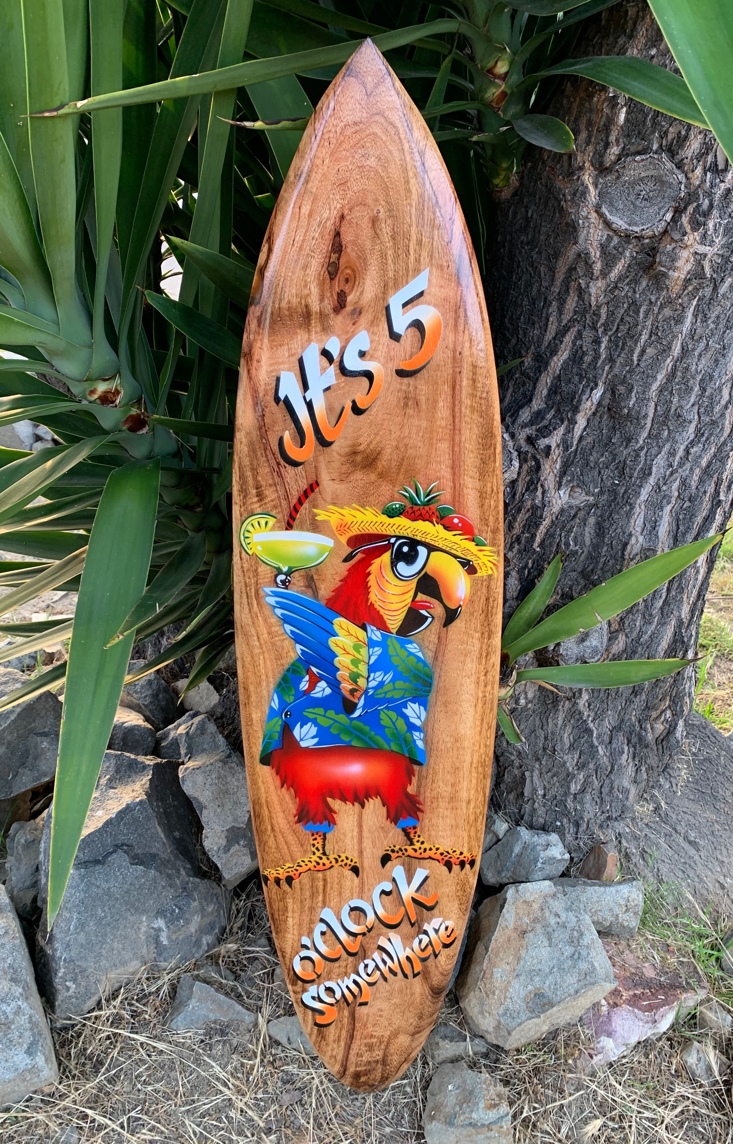 Wooden surfboard featuring a colorful parrot in a Hawaiian shirt and straw hat.