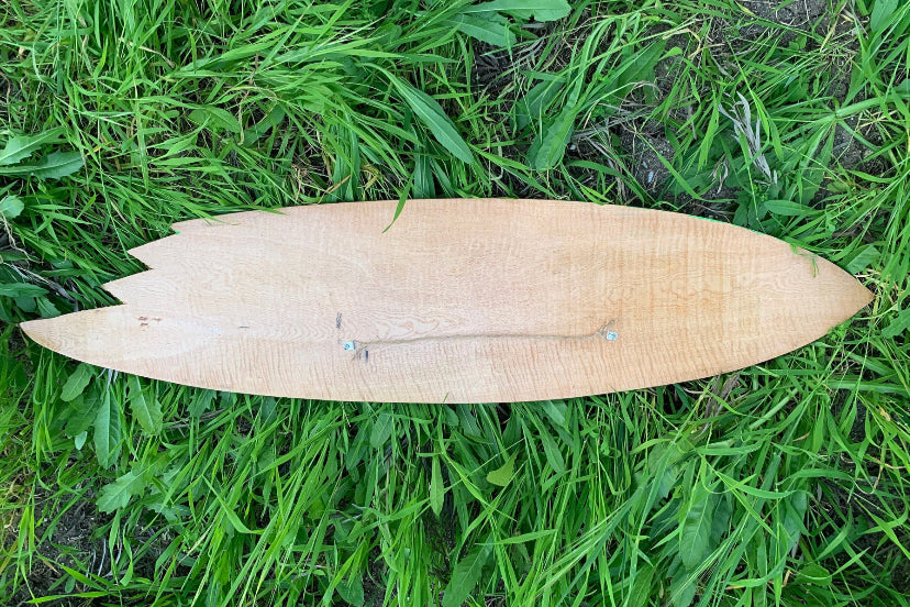wooden surfboard lying on green grass