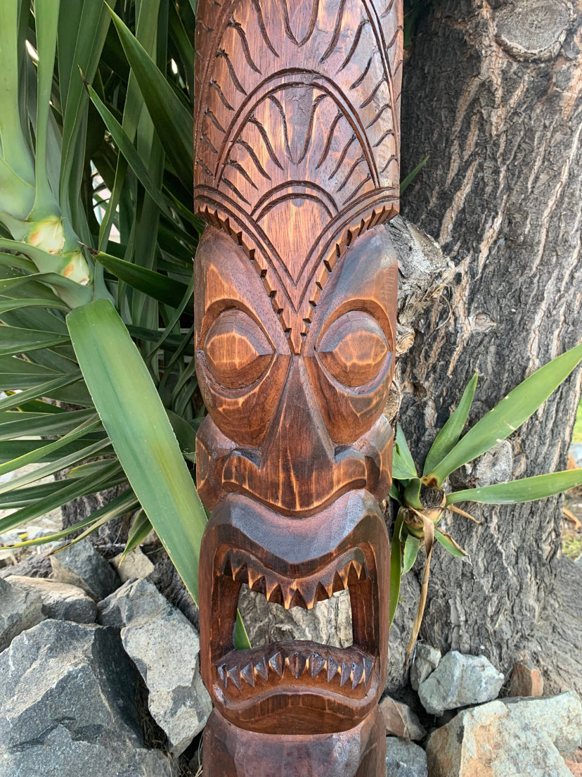 Wooden tiki carving with tribal patterns and a wide open mouth