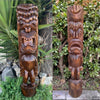 Carved wooden tiki totem pole sculpture with a fierce open-mouth face in a garden