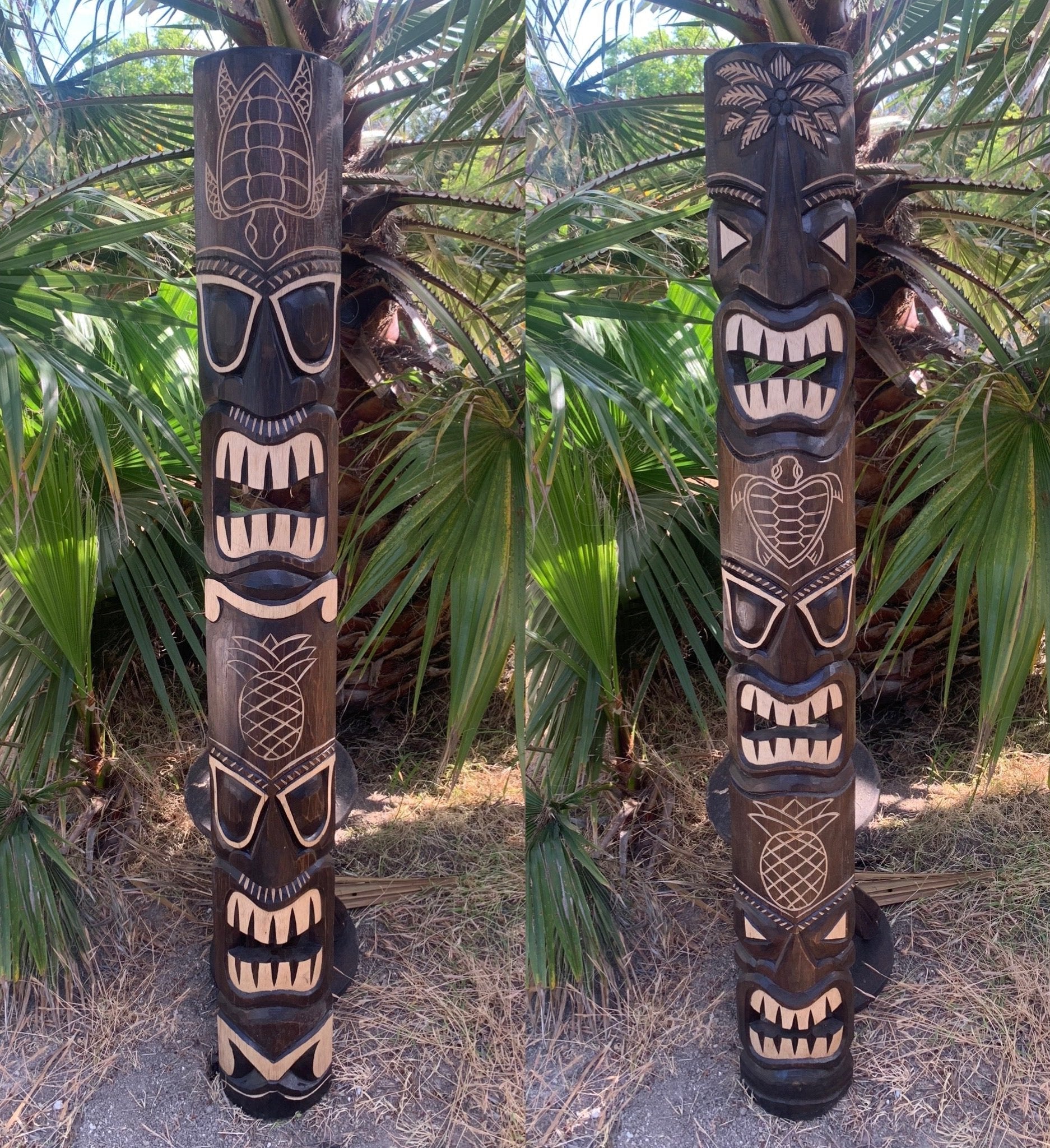 Two carved wooden tiki totem poles with faces and pineapple motifs in a tropical garden.