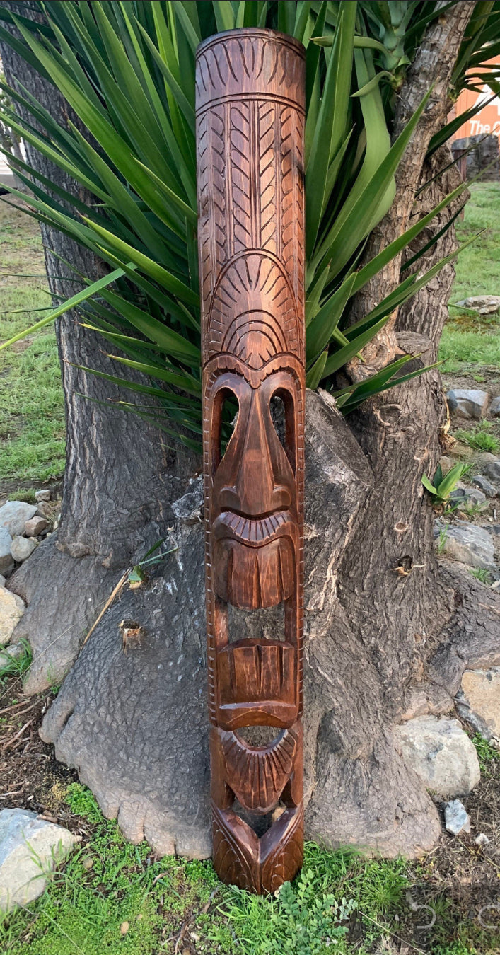 carved wooden totem pole featuring a large face design outdoors