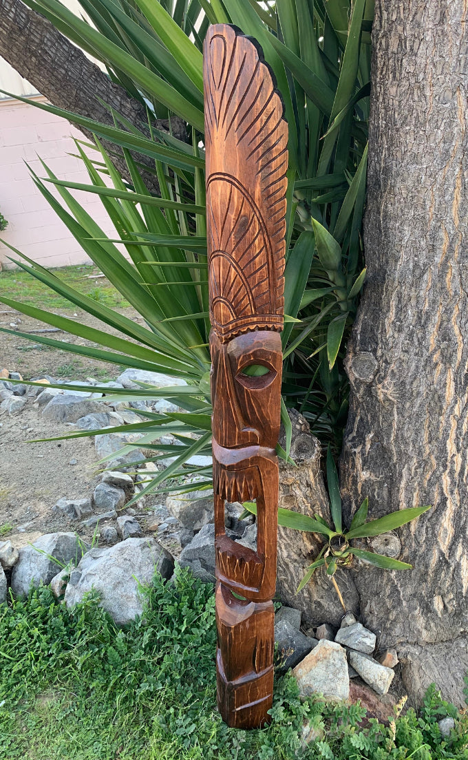 Carved wooden totem pole with a stylized face and feather-like patterns outdoors
