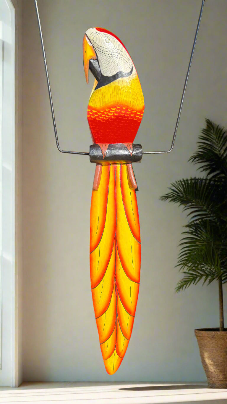 Colorful wooden toucan sculpture with orange and yellow tail hanging indoors