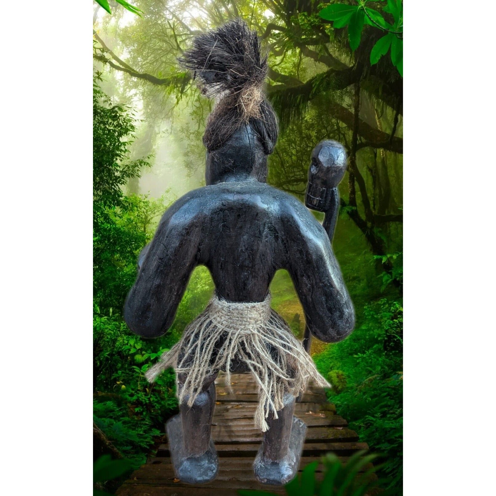 Back view of a dark wooden tribal statue with a rope skirt on a wooden path in a lush rainforest