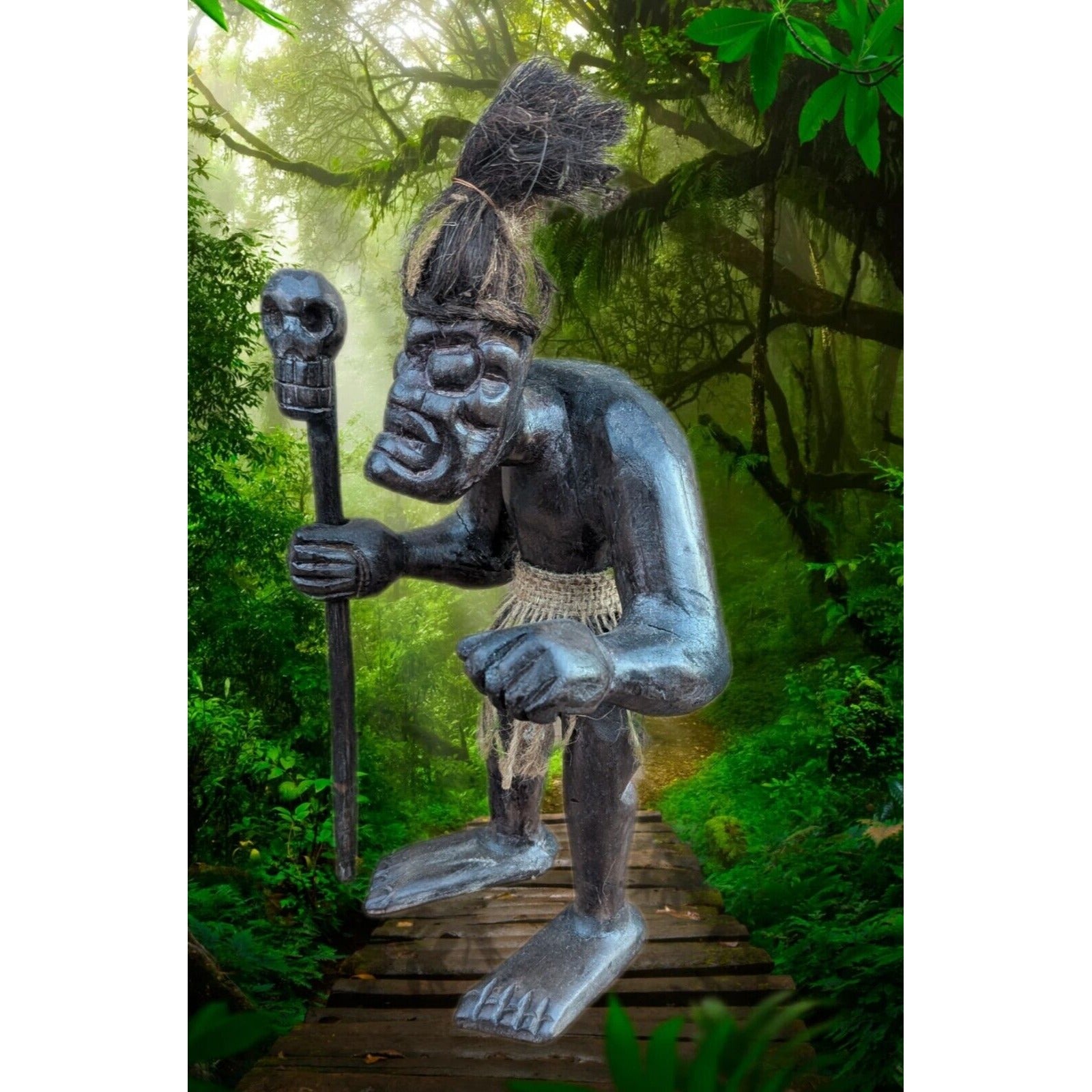Wooden tribal statue holding a staff on a lush jungle path