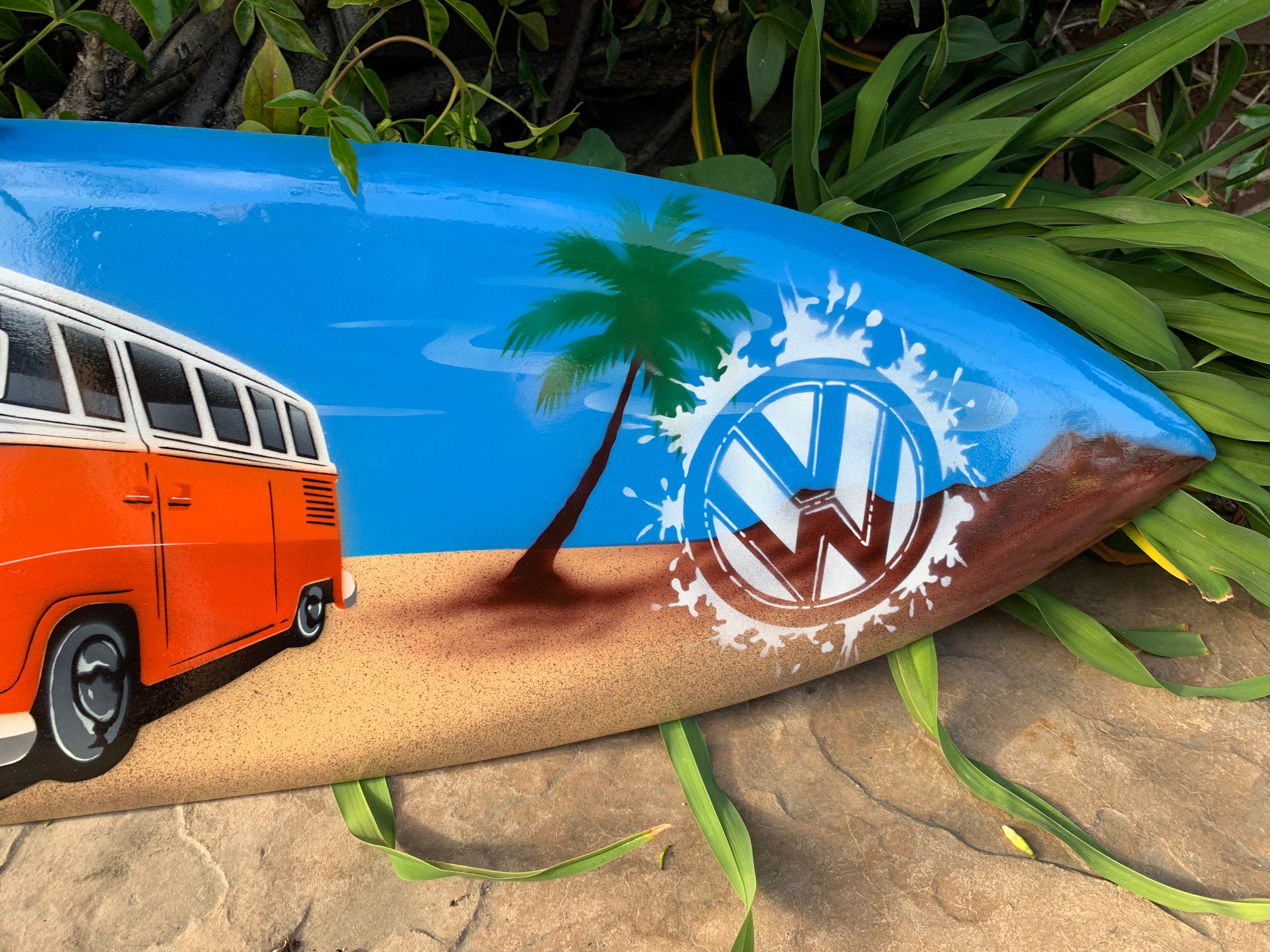 Beach-themed surfboard art with a palm tree and the VW logo splashing water