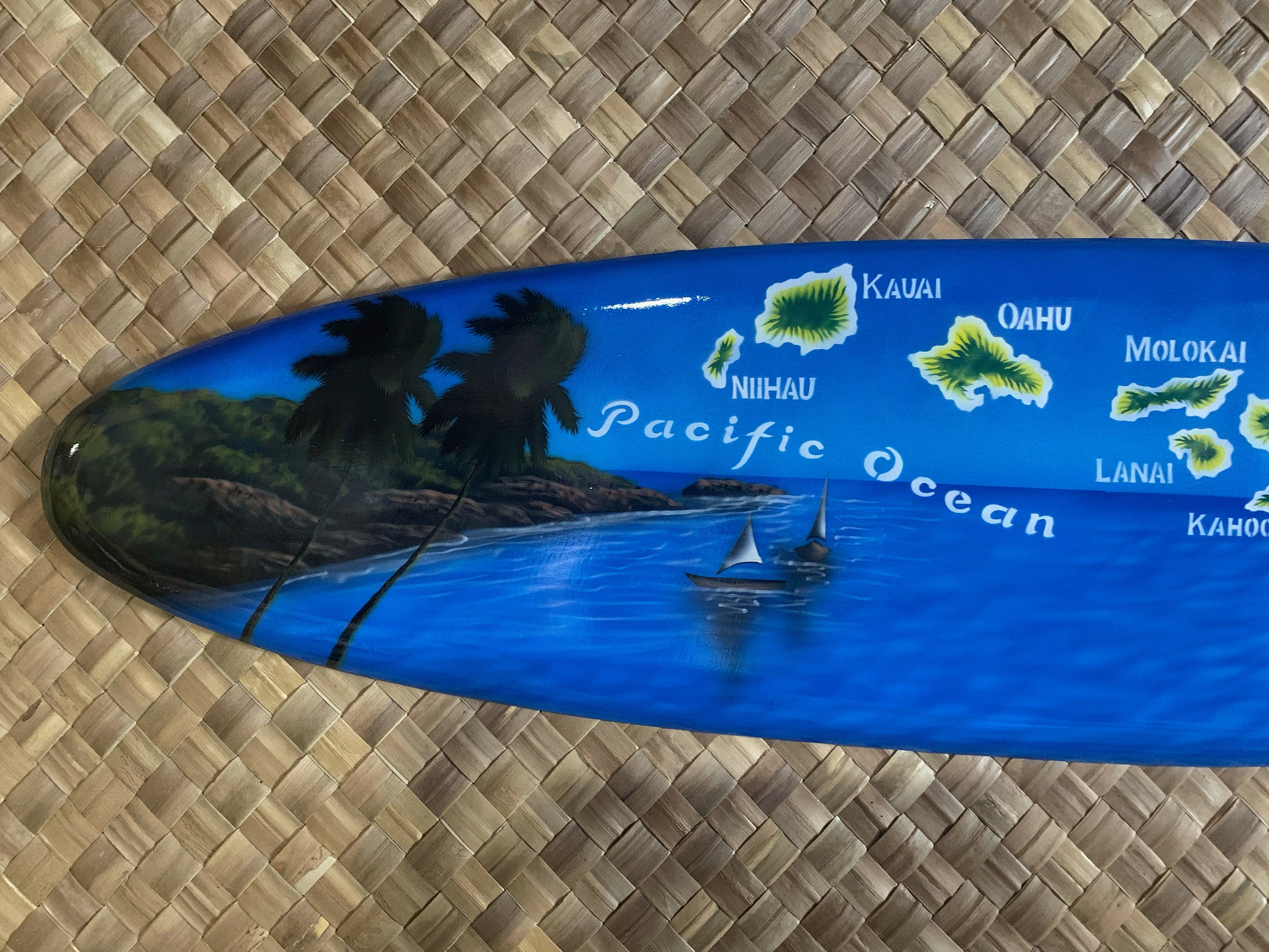 Blue Hawaiian-themed surfboard featuring palm trees, Pacific Ocean, and island silhouettes with sailboats