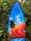 Blue surfboard with tropical sunset, palm trees, and ocean shoreline
