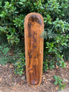 Canoe-shaped wooden tray with braided rope border outdoors.