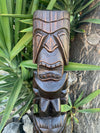 Carved wooden tiki statue among tropical green leaves