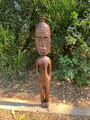 Carved wooden tiki statue standing in a garden among greenery