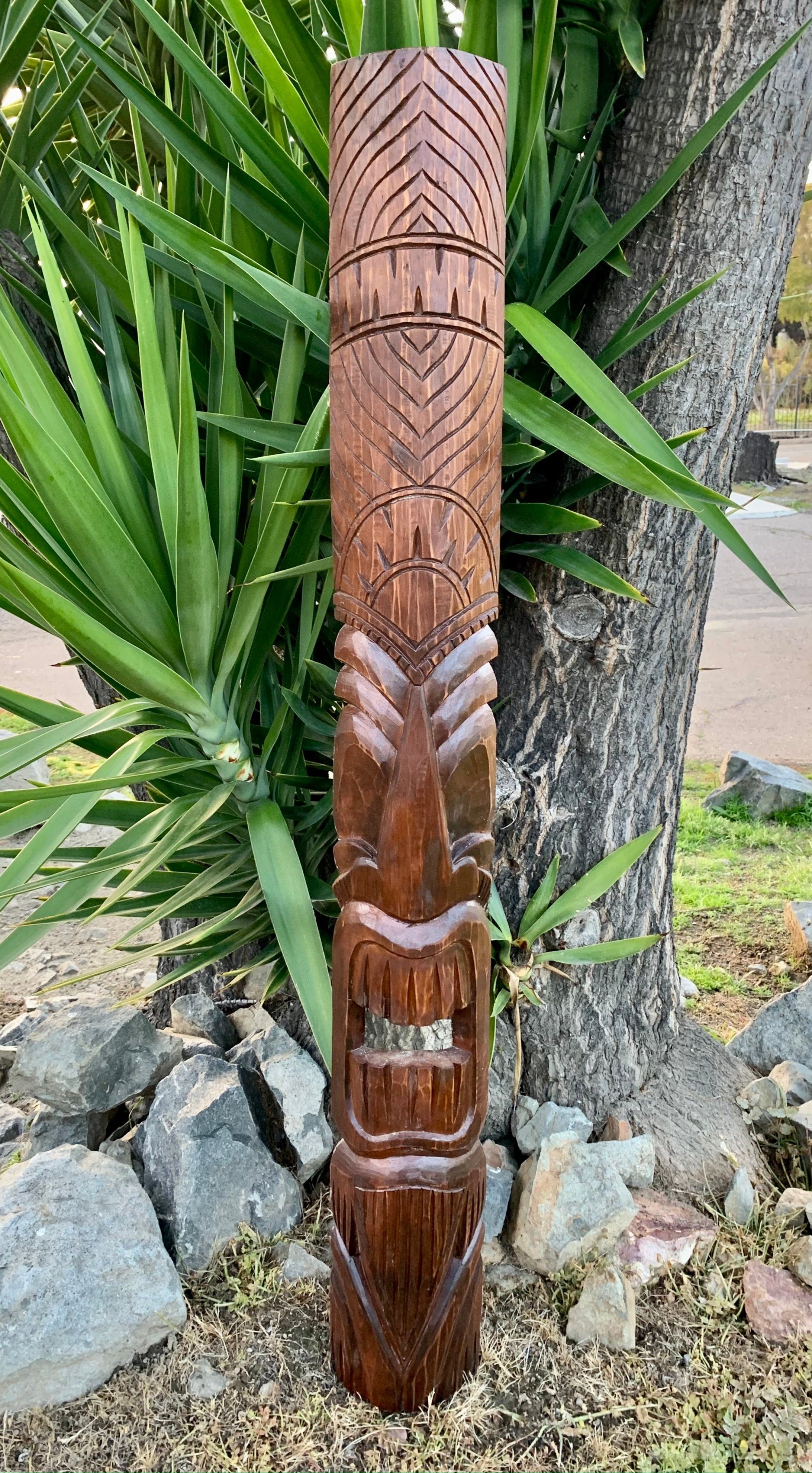 Carved wooden totem pole with geometric patterns in a garden setting