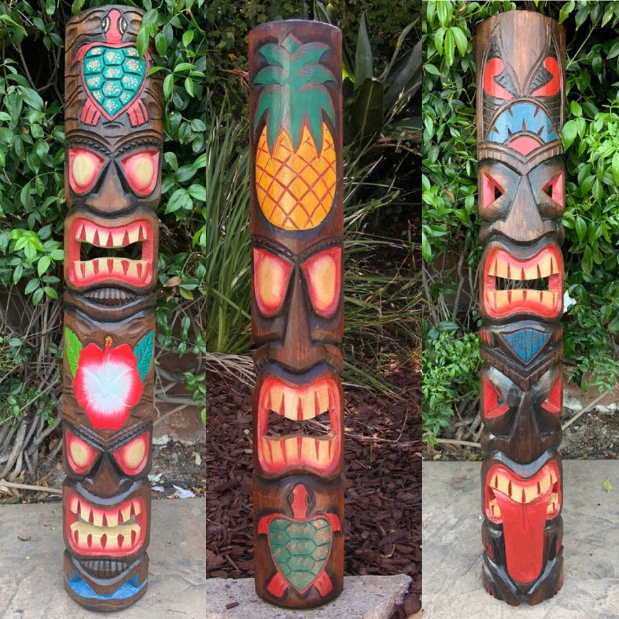 Three colorful carved tiki totem poles with dramatic faces in a garden setting