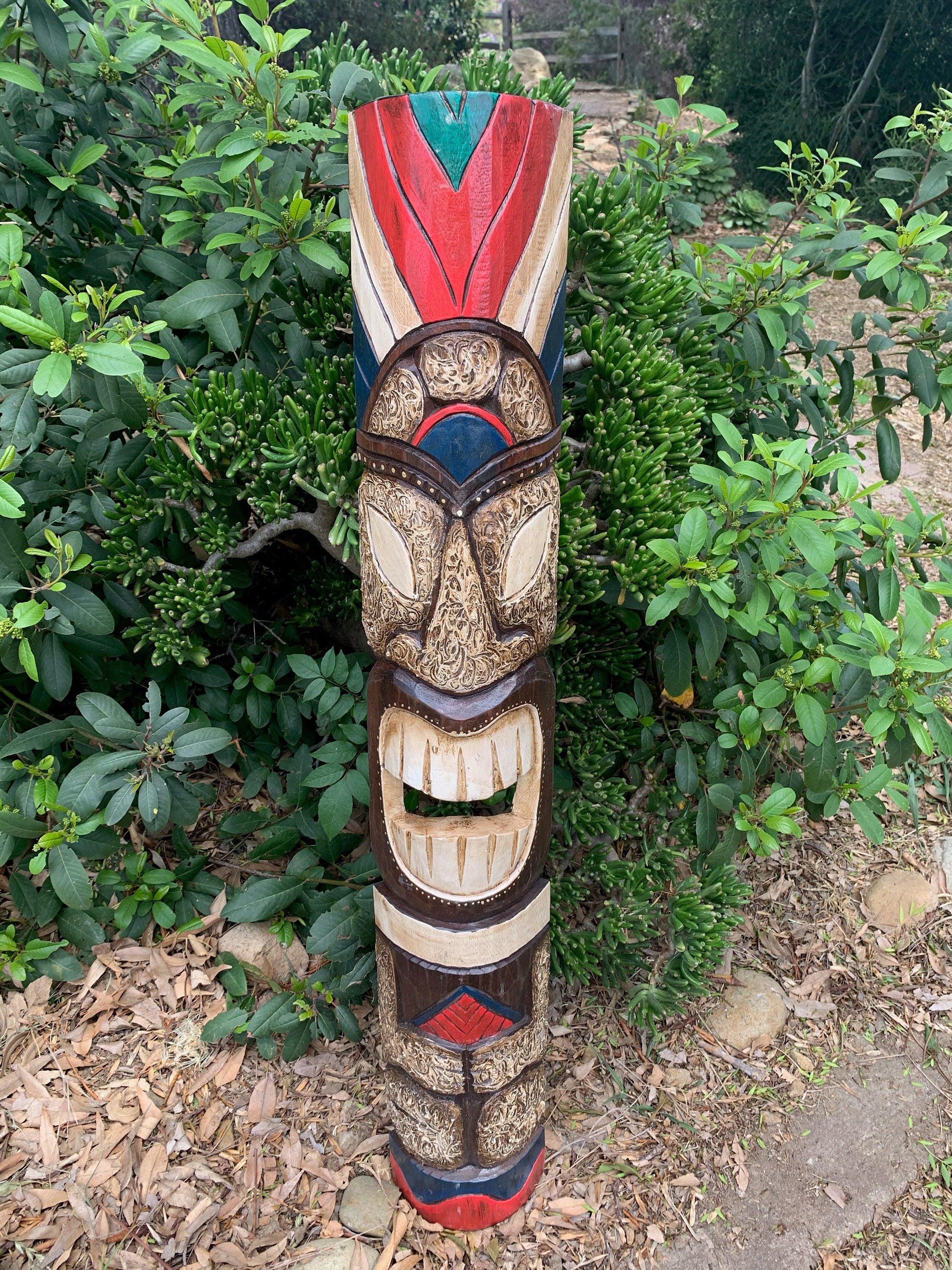 Colorful carved wooden totem pole in a garden with green shrubs