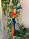 colorful rainbow toucan sculpture hanging among green houseplants